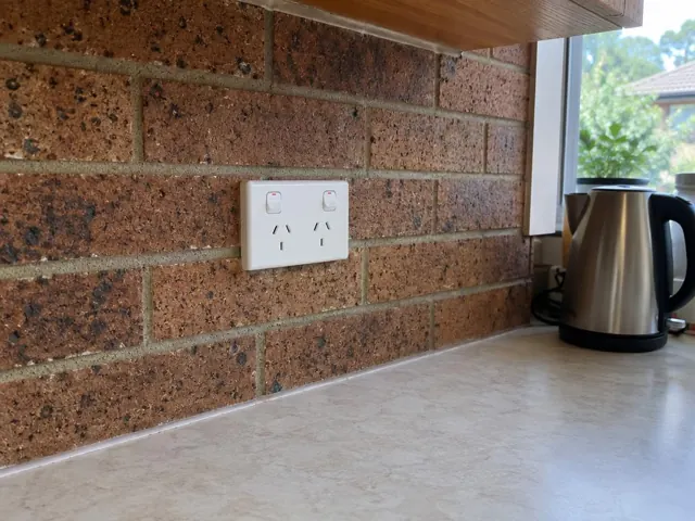 Double power point on a brick kitchen splashback above a benchtop in Bensville