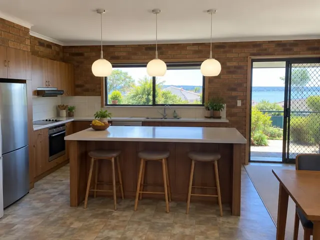 Three pendant lights above a kitchen island in a brick home interior in Empire Bay